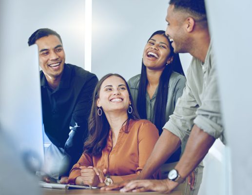 Shot of a diverse group of businesspeople standing together in the office and using a computer.