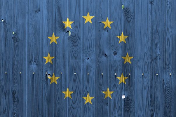 European union flag depicted in bright paint colors on old wooden wall close up. Textured banner on rough background